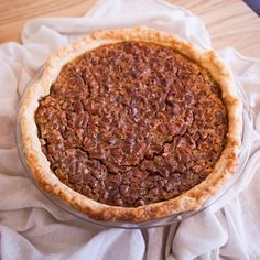 a pecan pie sitting on top of a white cloth covered table next to a knife