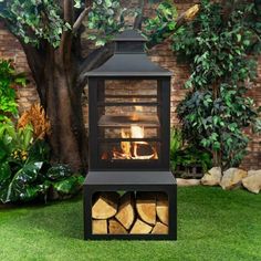 an outdoor fireplace with logs in the grass