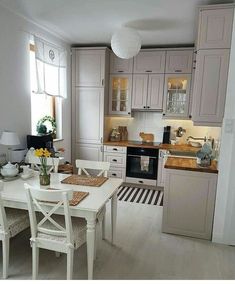 a white table and chairs in a room with light colored wood flooring on the walls