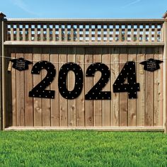 a wooden fence with a number sign hanging from it's side in the grass