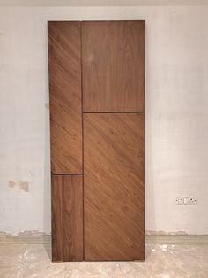 a large wooden door sitting in the middle of a room with white walls and tile flooring