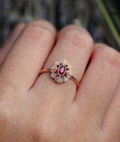 a close up of a person's hand wearing a ring with a red stone