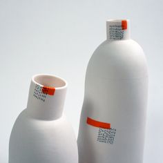 two white vases sitting next to each other on top of a table with an orange stripe