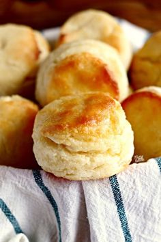 some biscuits are sitting in a basket on a towel and it looks like they have been baked