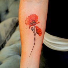 a woman's arm with a red flower tattoo on it