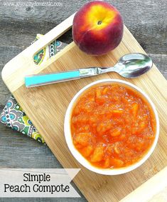 a bowl of peach compote on a cutting board next to an apple and spoon