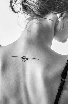 the back of a woman's neck with an arrow tattoo on her left shoulder