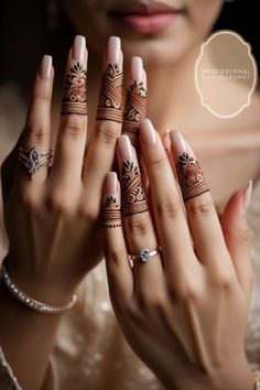 a woman holding her hands up with henna tattoos on their fingers and the other hand