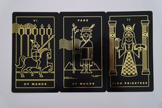 three playing cards with gold foil designs on black and white paper, depicting the four of wands