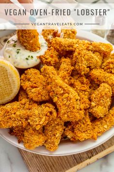 fried chicken with ranch dressing on a white plate next to a lemon wedge and sauce