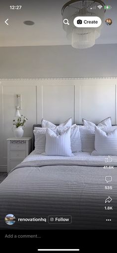 the bed is made with white linens and has pillows on each side, along with a chandelier hanging from the ceiling