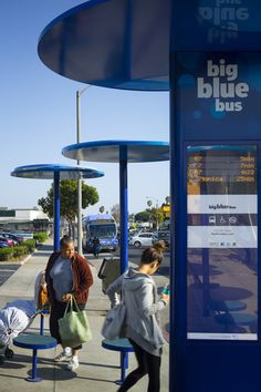 three people are standing at a bus stop