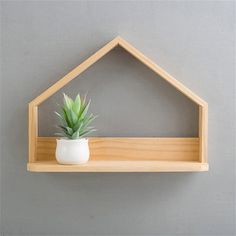 a potted plant is sitting in a wooden house shaped shelf on the wall next to a gray wall