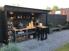 an outdoor bbq with wood stacked on the side and grilling area next to it