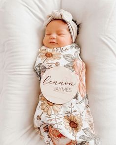 a baby wrapped in a blanket is sleeping on a white pillow with the name leonon jaymes