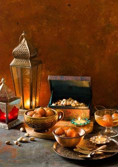 a table topped with bowls filled with oranges next to a lantern and other items