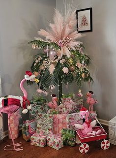 a christmas tree decorated with pink flamingos, gifts and other holiday decorations on a wooden floor