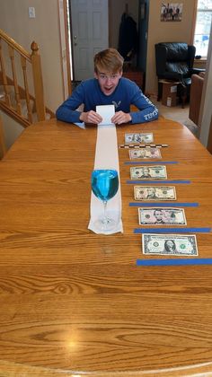 a boy sitting at a table with money on it