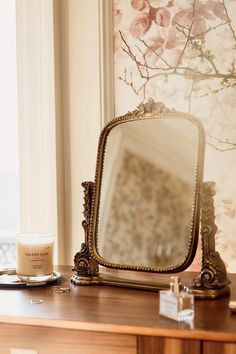 a mirror sitting on top of a wooden table next to a cup and saucer