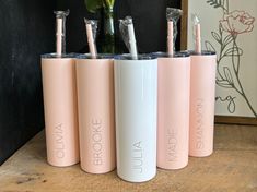 four pink and white tumbles sitting on top of a wooden table next to a vase with flowers