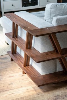 a wooden table sitting on top of a hard wood floor next to a white couch