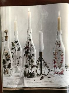 an open book with candles and flowers in glass bottles