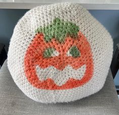 a crocheted pumpkin pillow sitting on top of a chair