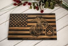 a wooden plaque with an american flag and marine emblem on it, next to flowers