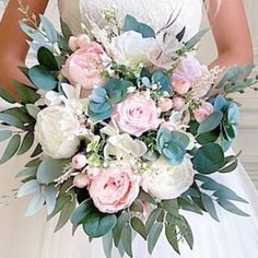 a bridal holding a bouquet of pink and white flowers with greenery on it