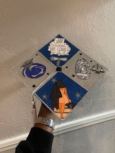 someone is holding up a graduation cap decorated with pictures and magnets on the ceiling