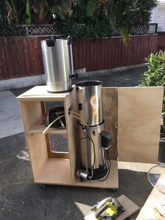 a machine is sitting on the ground next to some wood boxes and plants in front of it