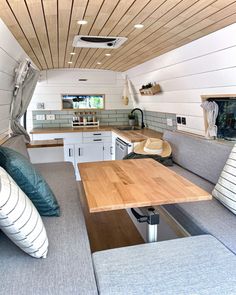 the interior of a camper with wood flooring and white walls, wooden ceiling