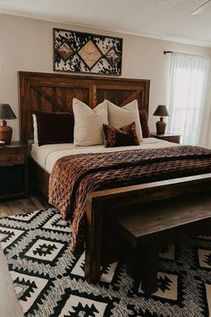 a bedroom with a large bed and wooden headboard on top of a black and white rug