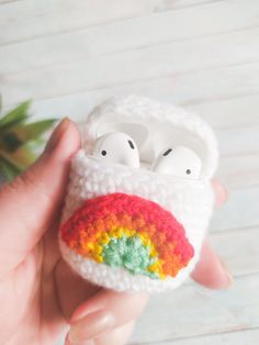 a hand holding an airpods case made to look like a rainbow