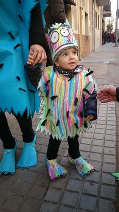 a small child dressed in costume standing next to two adults and one is holding the hand of someone's hand