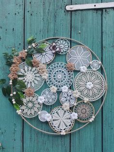 a circular doily with flowers and leaves is hanging on a blue wooden wall next to a pair of scissors