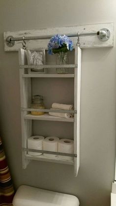 a white toilet sitting in a bathroom next to a shelf with rolls of toilet paper on it