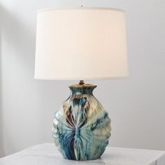 a blue and white vase sitting on top of a table next to a lampshade