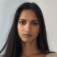 a woman with long black hair is looking at the camera