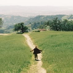 a person walking down a dirt road in the middle of a field