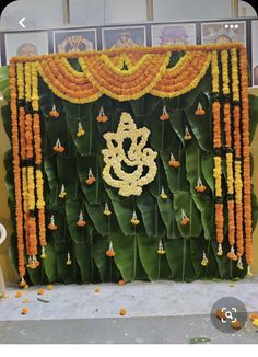 an arrangement of orange and yellow flowers on display in front of a green wall with gold decorations