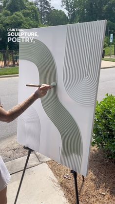 a man holding a paintbrush in front of a large poster