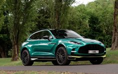 a green porsche cayen is parked on the side of the road in front of some trees