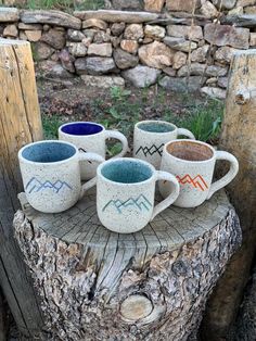 four mugs sitting on top of a tree stump