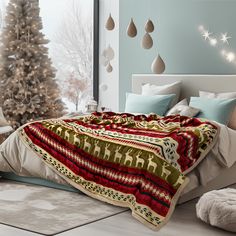 a bed with a blanket on top of it next to a christmas tree