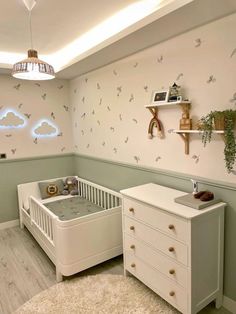 a baby's room with a crib, dresser and wall decals on the walls