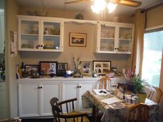 the dining room table is set for two with pictures on the wall and cupboards behind it