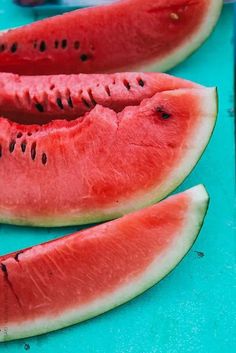 three slices of watermelon sitting on top of a blue table next to each other