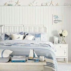 a bed with blue and white striped comforter next to a wall mounted fish on the wall