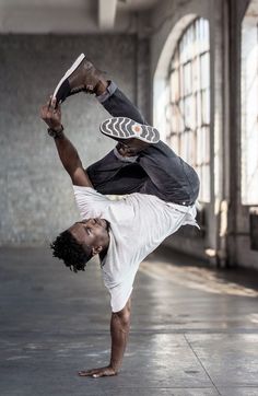 a man is doing a handstand in an empty room with windows behind him